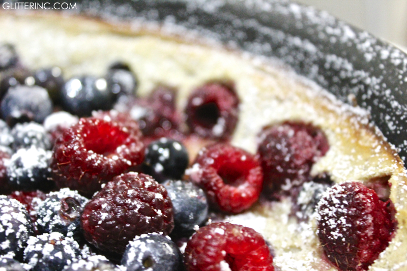 dutch baby pancake ith powdered sugar raspberries and blueberries close-up - recipe - glitterinc.com