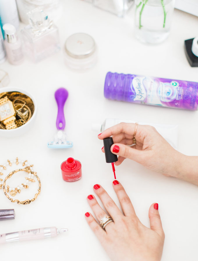 woman applying red nail polish on her finger nails 