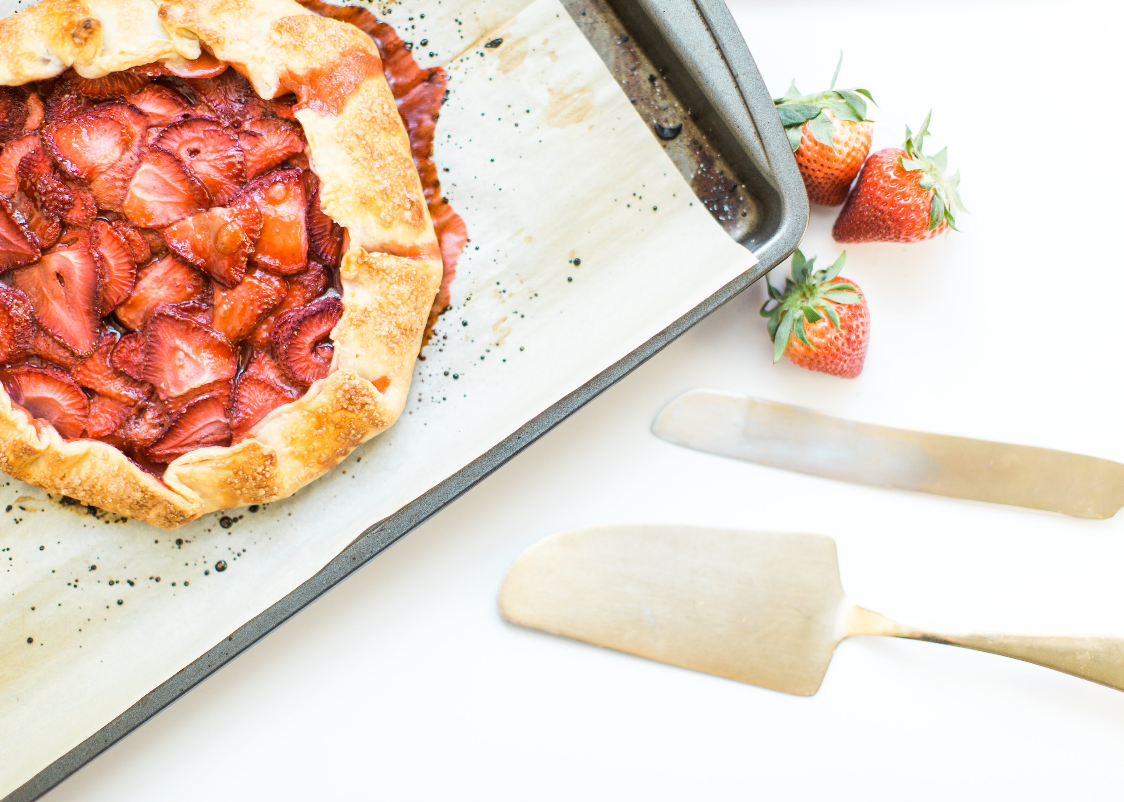 Flaky pie dough, a sweet jam and fresh strawberry filling, and a sprinkling of turbinado sugar on the crust, makes this simple strawberry galette or crostata, a.k.a., pie made easy using store-bought crust, the stuff of dreams. Click through for the recipe. #pie #strawberrypie #strawberrygalette #strawberrycrostata #crostata #galette #simplesummerdessert #summerdessert #springdessert #simpledessert #easydessert #easypie #simplepie | glitterinc.com | @glitterinc