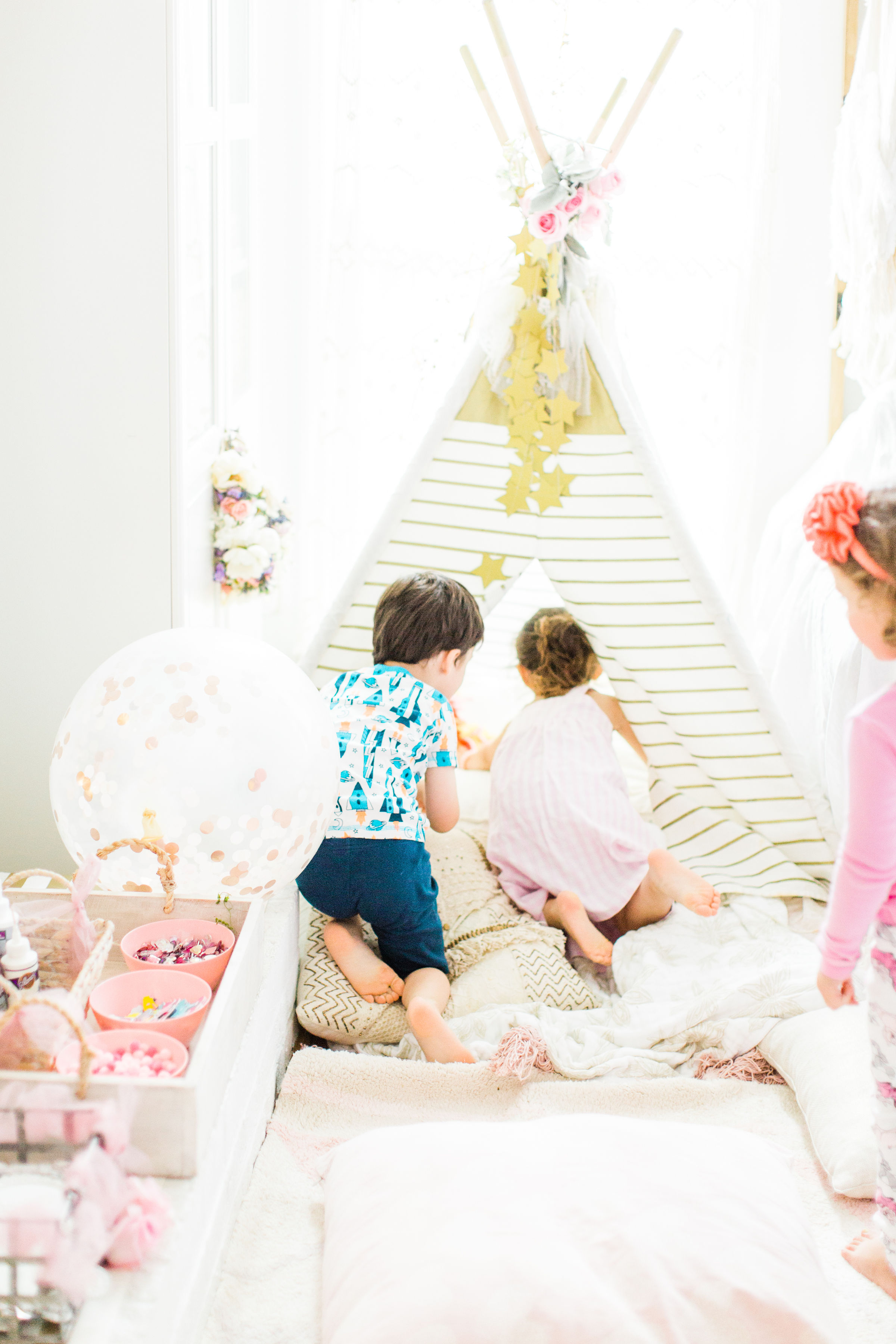 Ready to throw one beautiful and memorable princess pajama birthday party? Have we got some inspiration for you! We turned our living room into one giant slumber party and covered every available space with sheets, pillows, and blankets, plus gorgeous pink florals, a cozy tent lounge, a DIY magic mirror decorating activity for the kids, a dress-up station with crowns, wands, and wings, a pin the tail on the unicorn game, and so much more. Click through for the party details. #party #pajamaparty #princessparty #dressup | glitterinc.com | @glitterinc