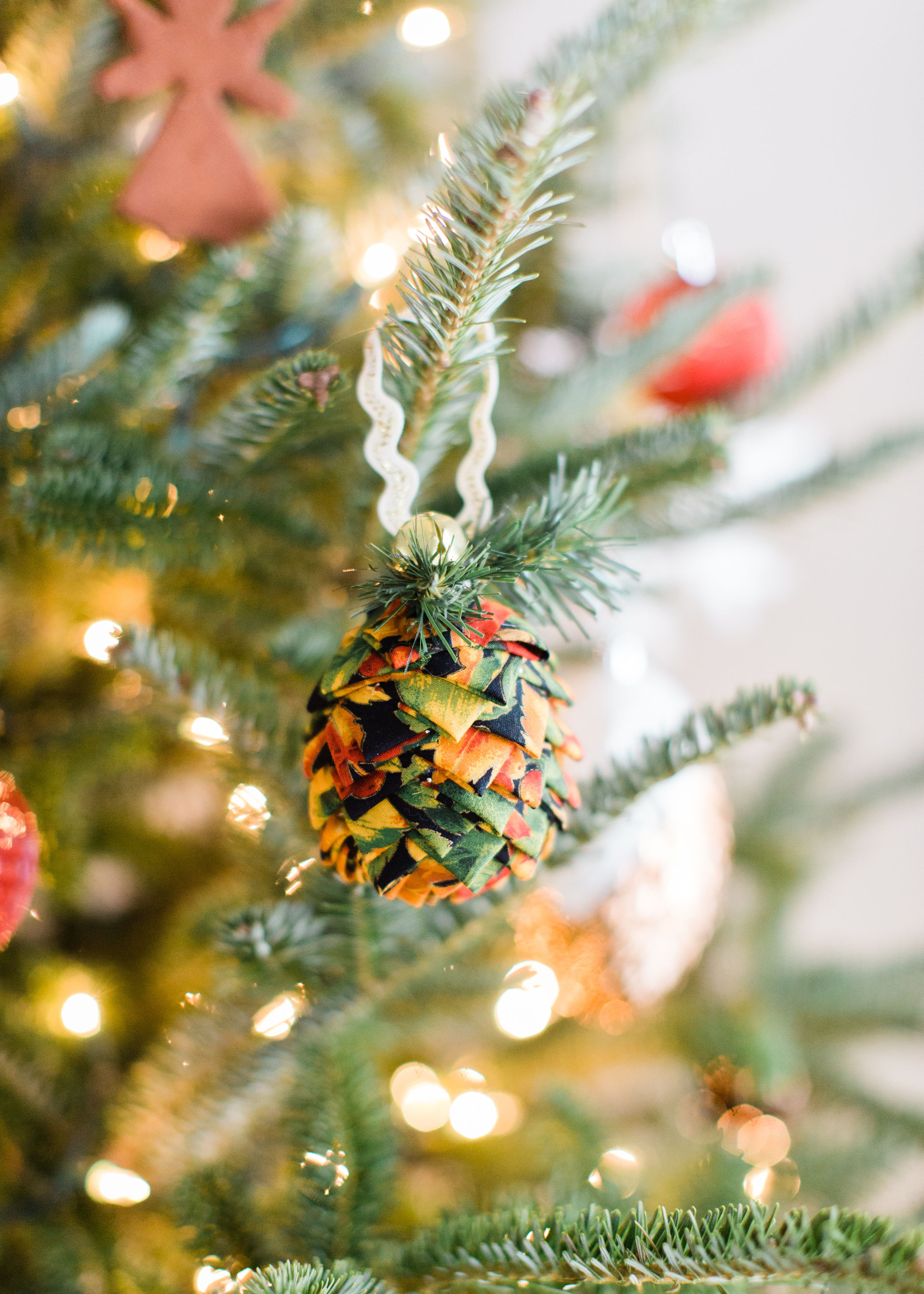 Looking for a fun Christmas craft to make this holiday season? DIY folded fabric pinecones make the prettiest ornaments, are perfect as gift toppers, and use up leftover fabric scraps - no sewing required. Click through for the details. #diyfabricpinecones #christmascraft #holidaycraft #holidaydiy #christmasdiy #nosew | glitterinc.com | @glitterinc