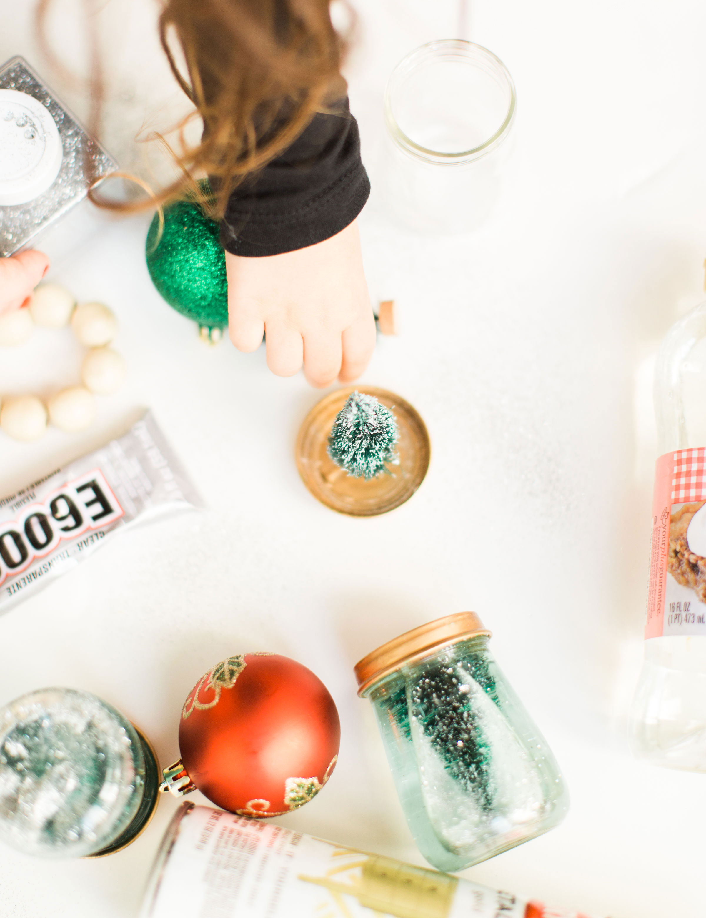 Glitter DIY snow globes are fun to make, are a great craft to do with kids, and double as a calm down sensory bottle for a little quiet time on days when the whole family is going a little stir crazy! Click through for the details. #kidsdiy #kidscraft #diysnowglobes #howtomakesnowglobes #sensorybottles #sensoryglobes #toddlercraft #wintercraft #christmas #christmasdiy #christmascraft | glitterinc.com | @glitterinc