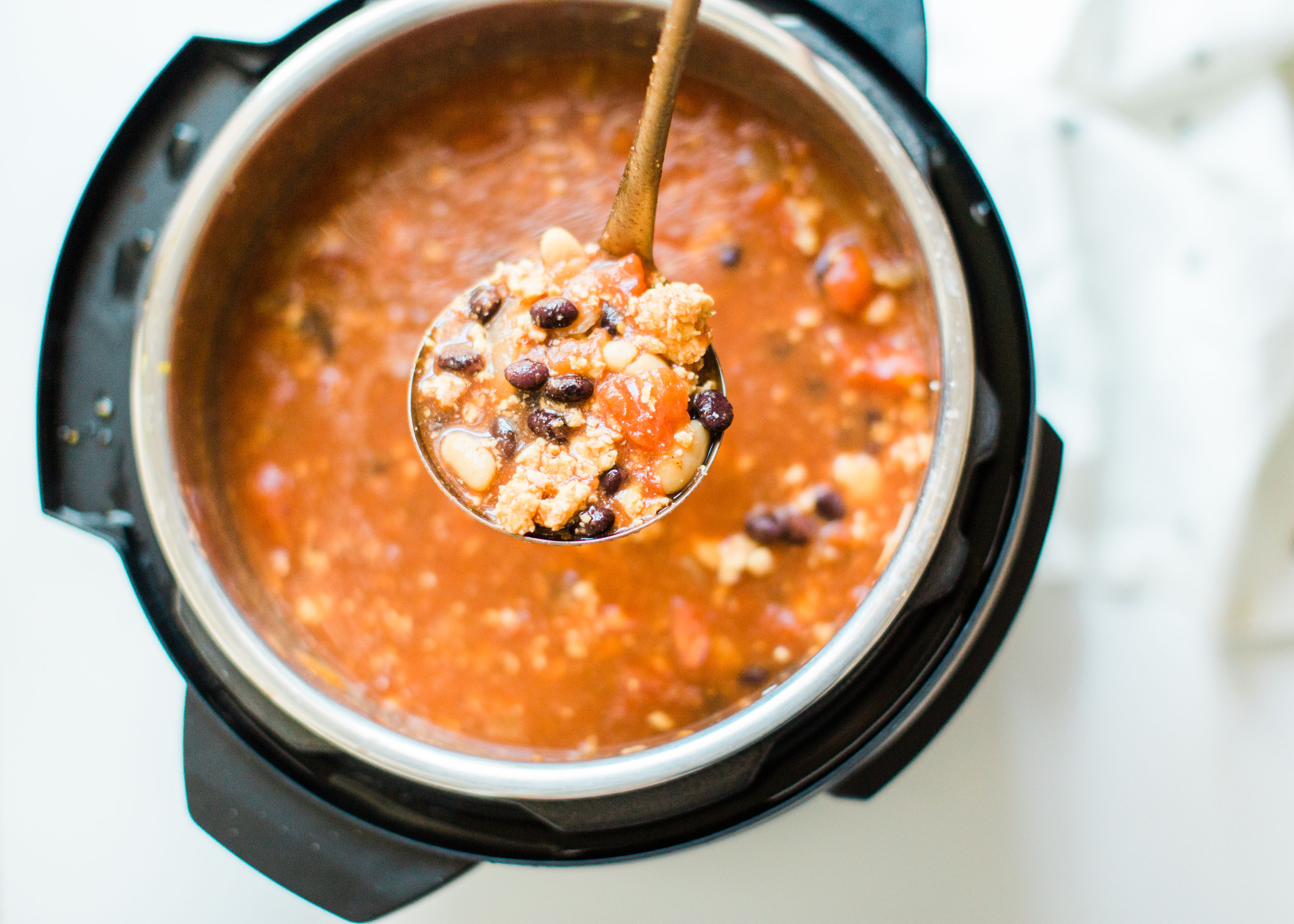 This easy and delicious ground chicken chili all comes together in an Instant Pot or crockpot. Serve this made ahead chili with yummy toppings and cornbread and enjoy an incredible, hearty, healthy, and simple meal. Click through for the recipe. | glitterinc.com | @glitterinc