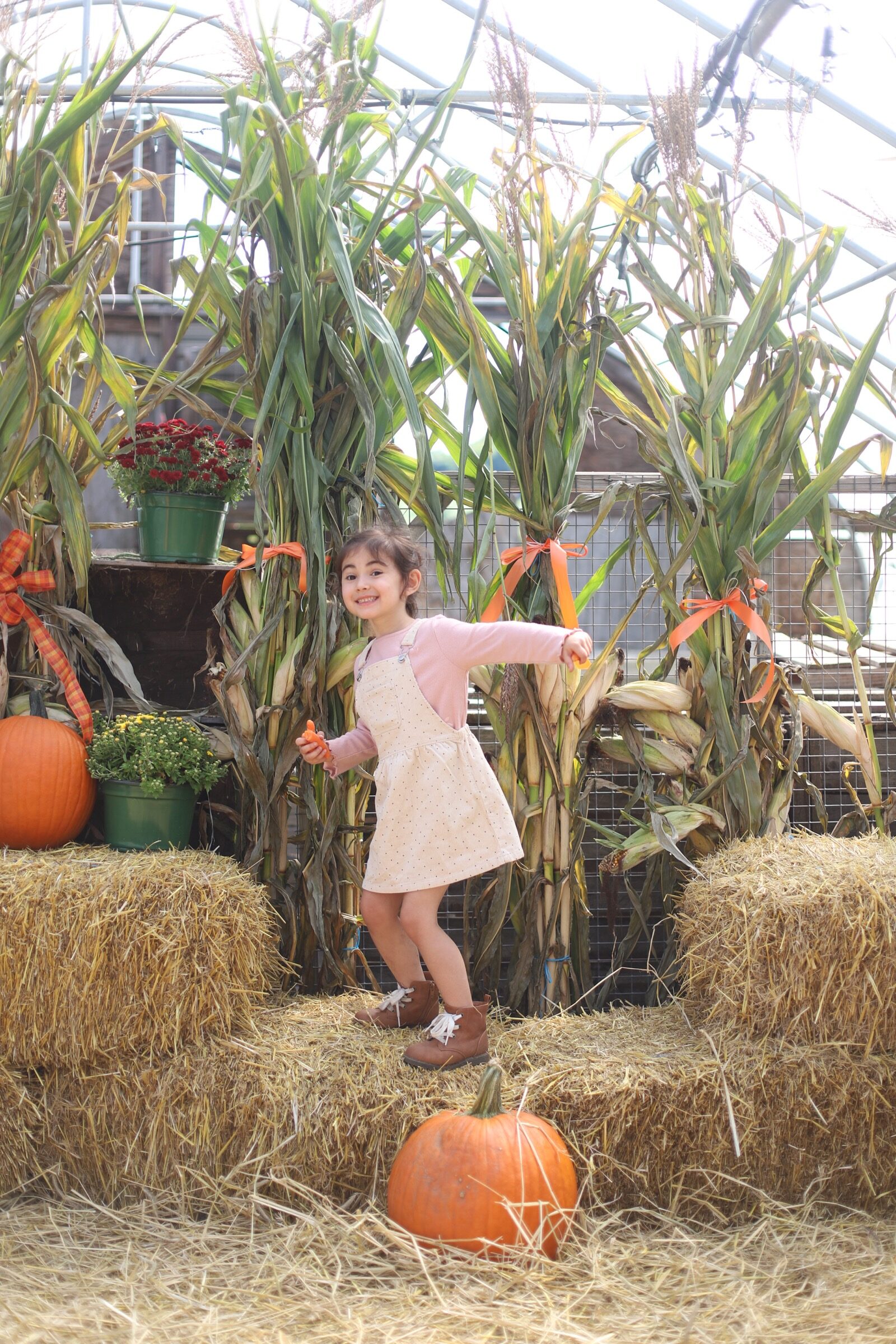 A little girl posing with haystacks and pumpkins at Brooksby Farm in Peabody, Massachusetts // Fall Bucket List | glitterinc.com | @glitterinc