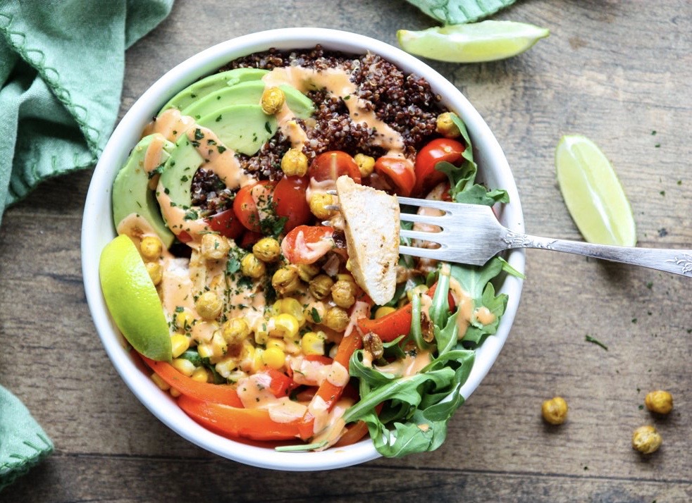 The ingredients for these healthy burrito bowls start out on a sheet pan. Everything gets roasted together, including the crispy chickpeas, before being assembled in bowls.