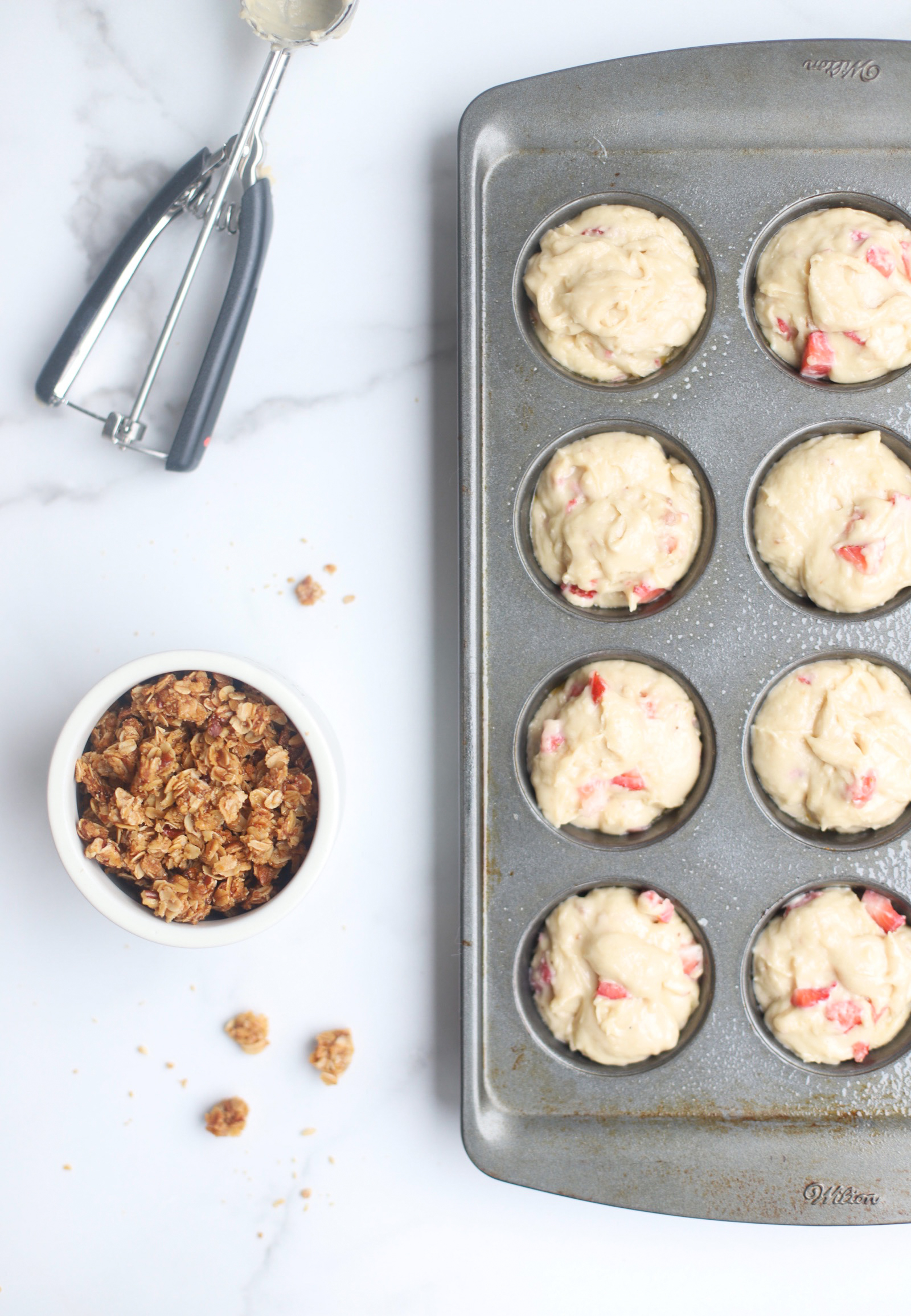 Bake up a batch of these decadently fluffy and moist bakery-style Strawberry Yogurt Granola Crumble Muffins, made with rich Greek yogurt, full of fresh strawberry flavor, and topped with our favorite homemade classic granola crumble. Click through for the recipe. | glitterinc.com | @glitterinc