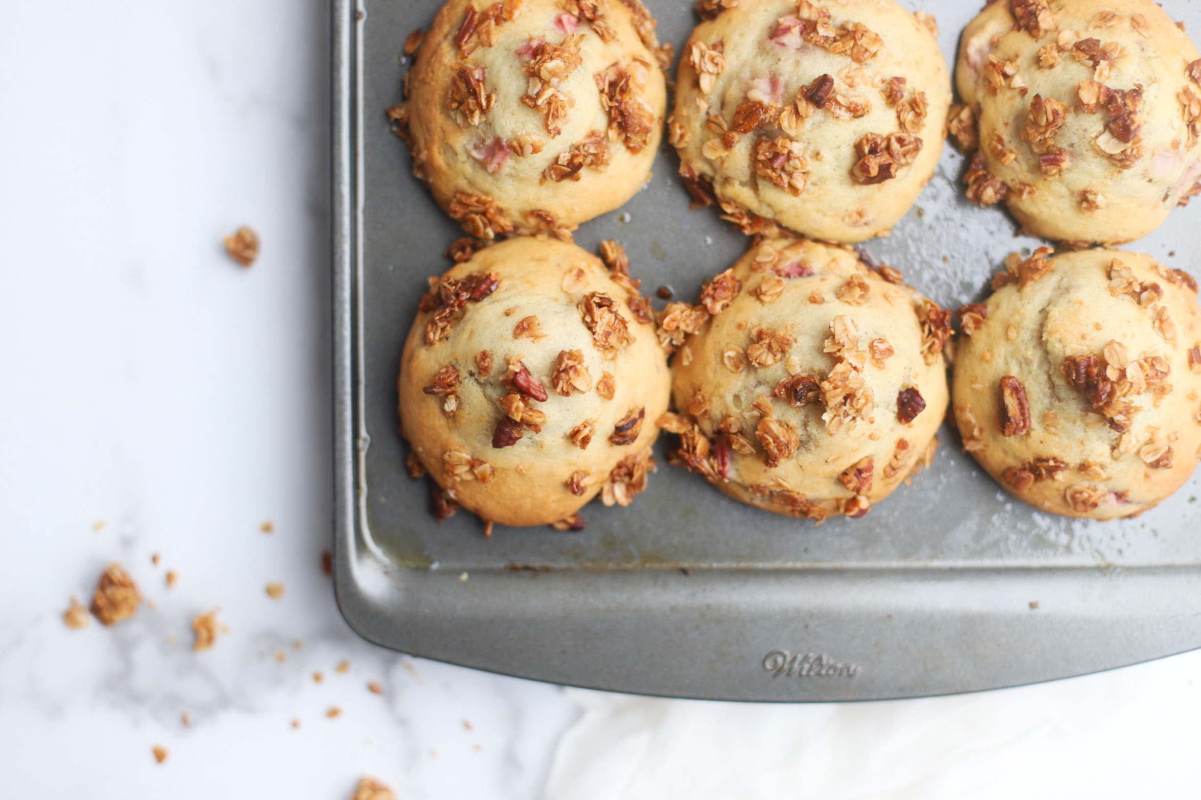 Bake up a batch of these decadently fluffy and moist bakery-style Strawberry Yogurt Granola Crumble Muffins, made with rich Greek yogurt, full of fresh strawberry flavor, and topped with our favorite homemade classic granola crumble. Click through for the recipe. | glitterinc.com | @glitterinc