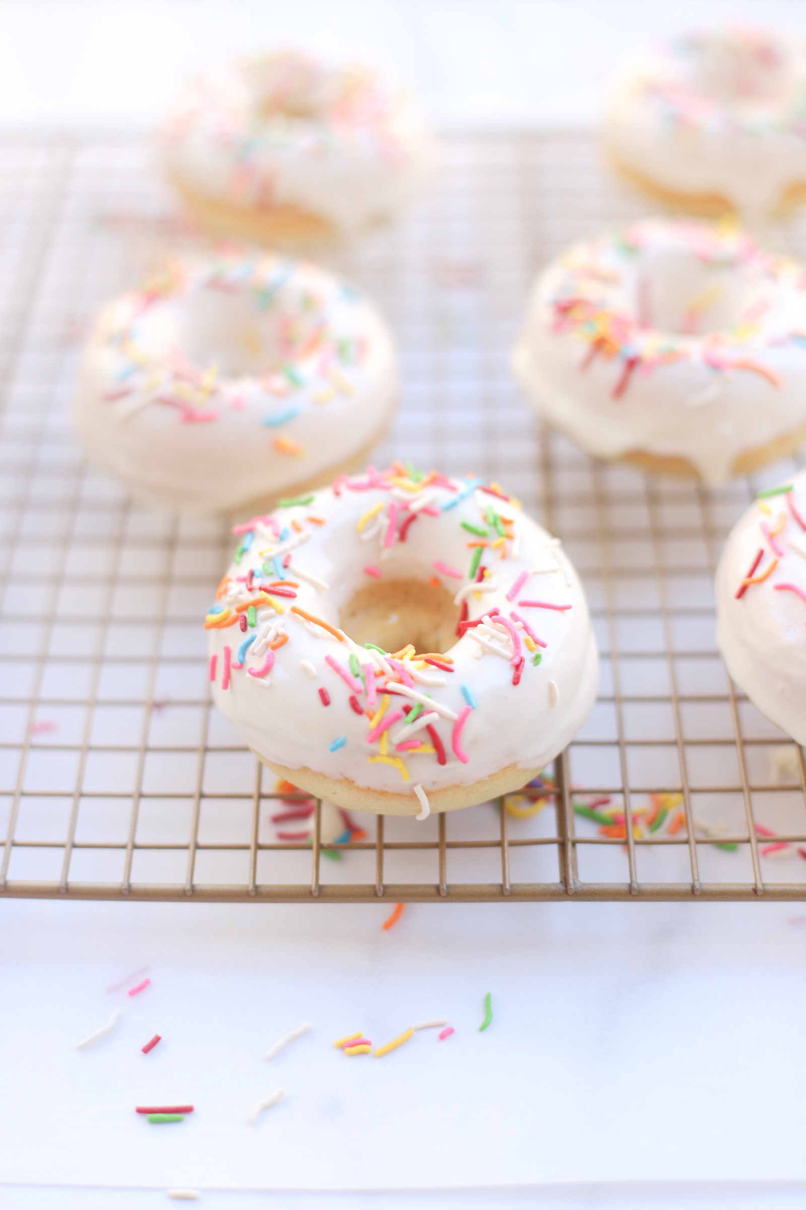 Totally fluffy, soft, moist, and amazingly dairy-free, you would never know that these crowd-pleasing donuts are vegan, and baked, to keep this delicious dessert a little healthier. These baked vegan vanilla donuts are the perfect treat for birthday parties, holidays, gifting, bake sales, and more! Click through for the recipe. | glitterinc.com | @glitterinc