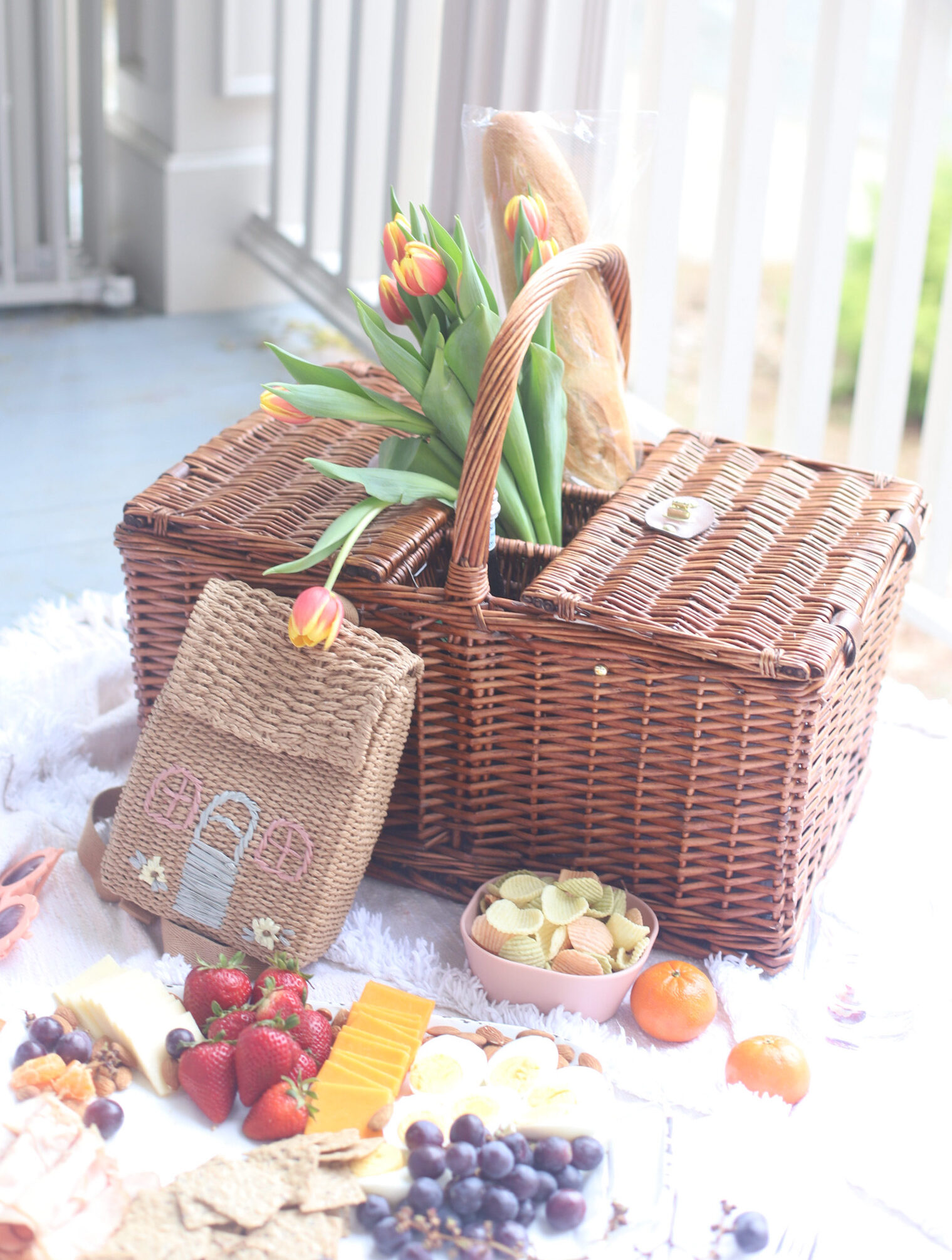 a picnic basket surrounded by fruits, cheese, and crackers 