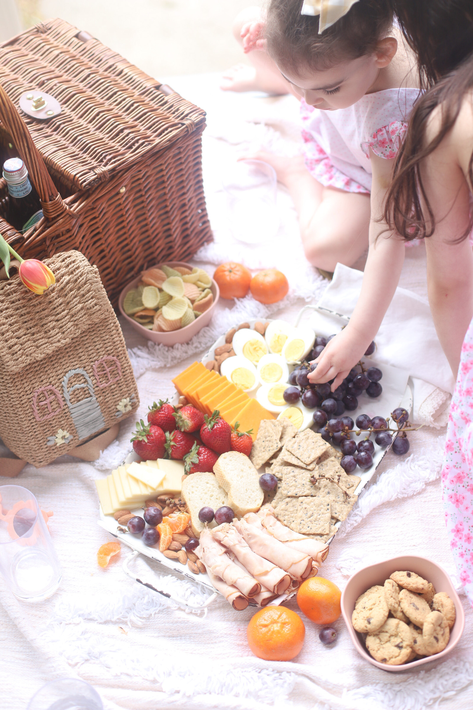 two kids, a picnic basket, and a charcuterie board