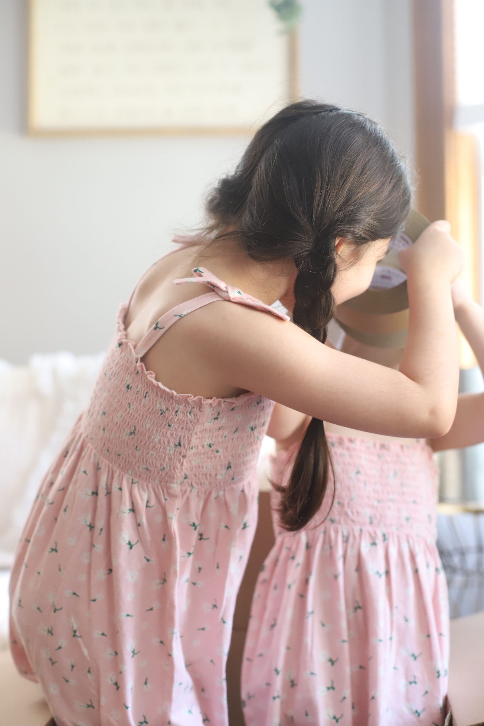 two girls wearing identical dress and playing with a packing tape