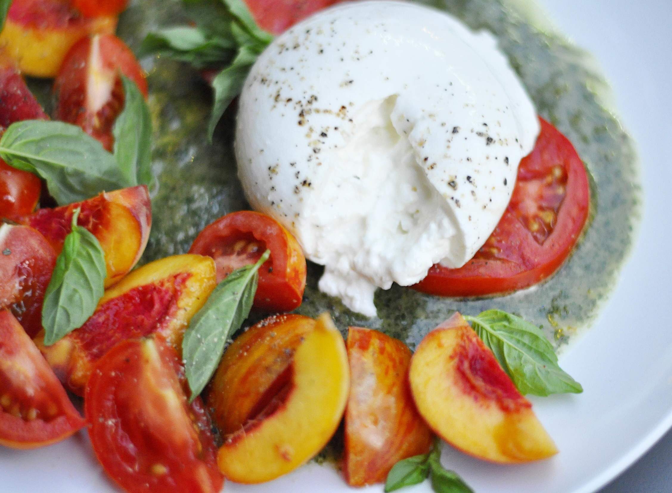 Peach, Tomato, and Burrata Salad on a white plate