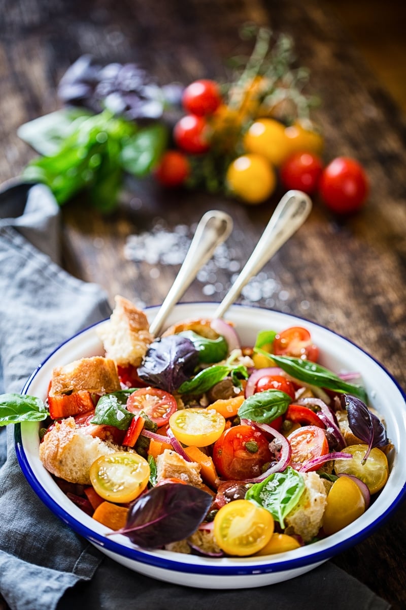 Tuscan Panzanella Salad on a white bowl with two serving spoon for Incredible Summer Salad Recipes