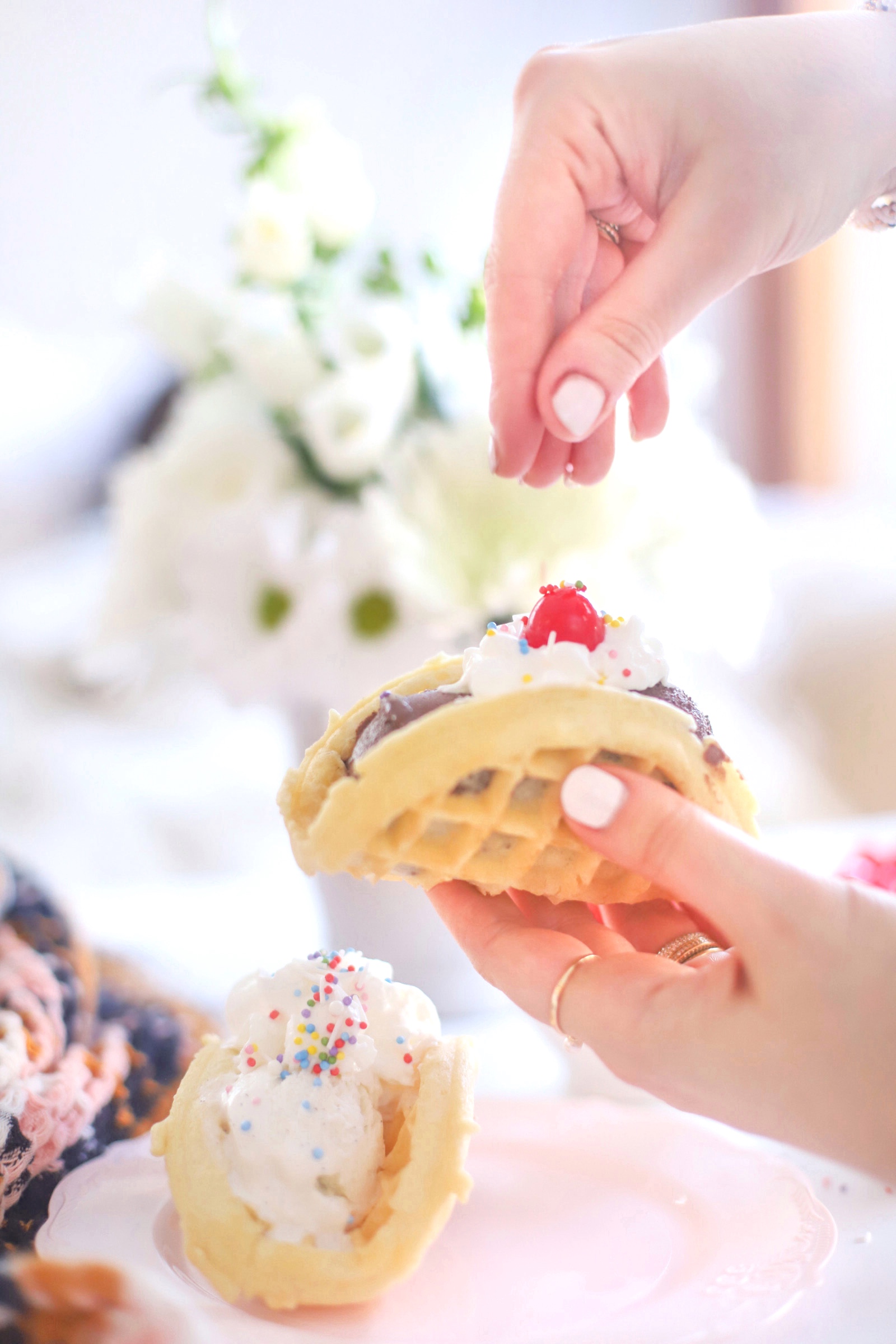 woman sprinkling dessert toppings on a pancake with ice cream