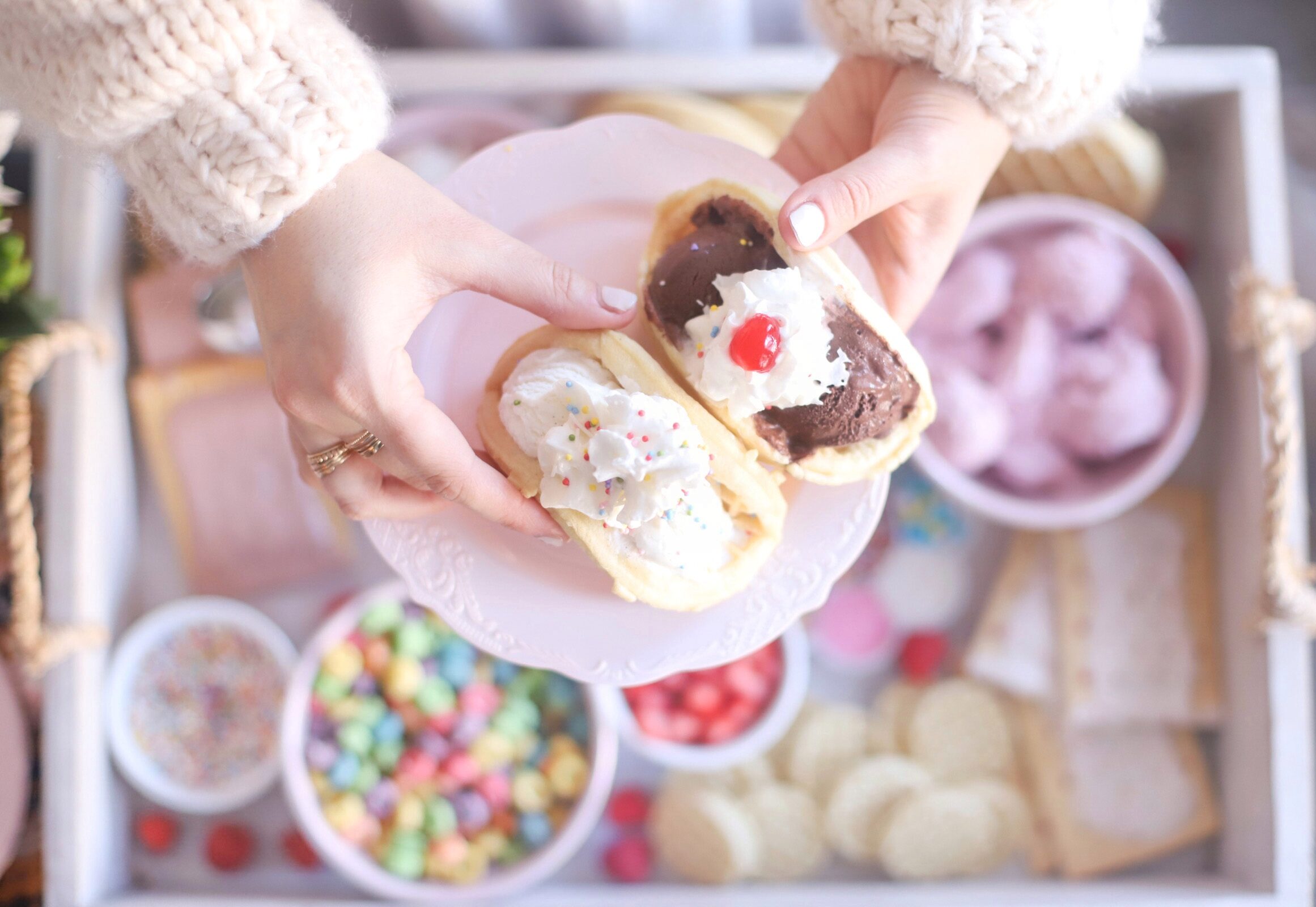 woman holding a plate with two desserts on it