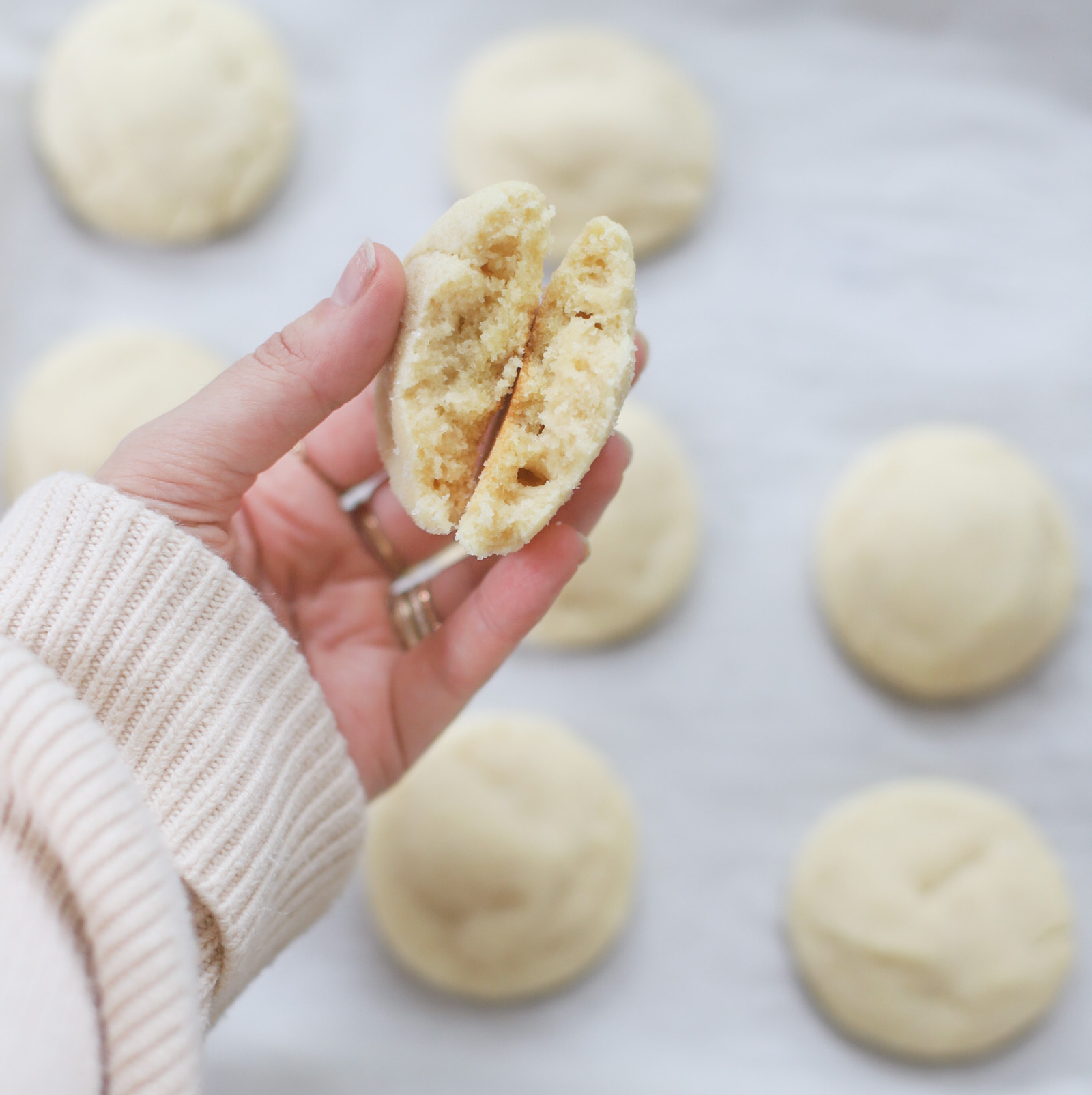 a woman's hand holding four pieces of Dairy Free Sprinkle Sugar Cookies without sprinkles 