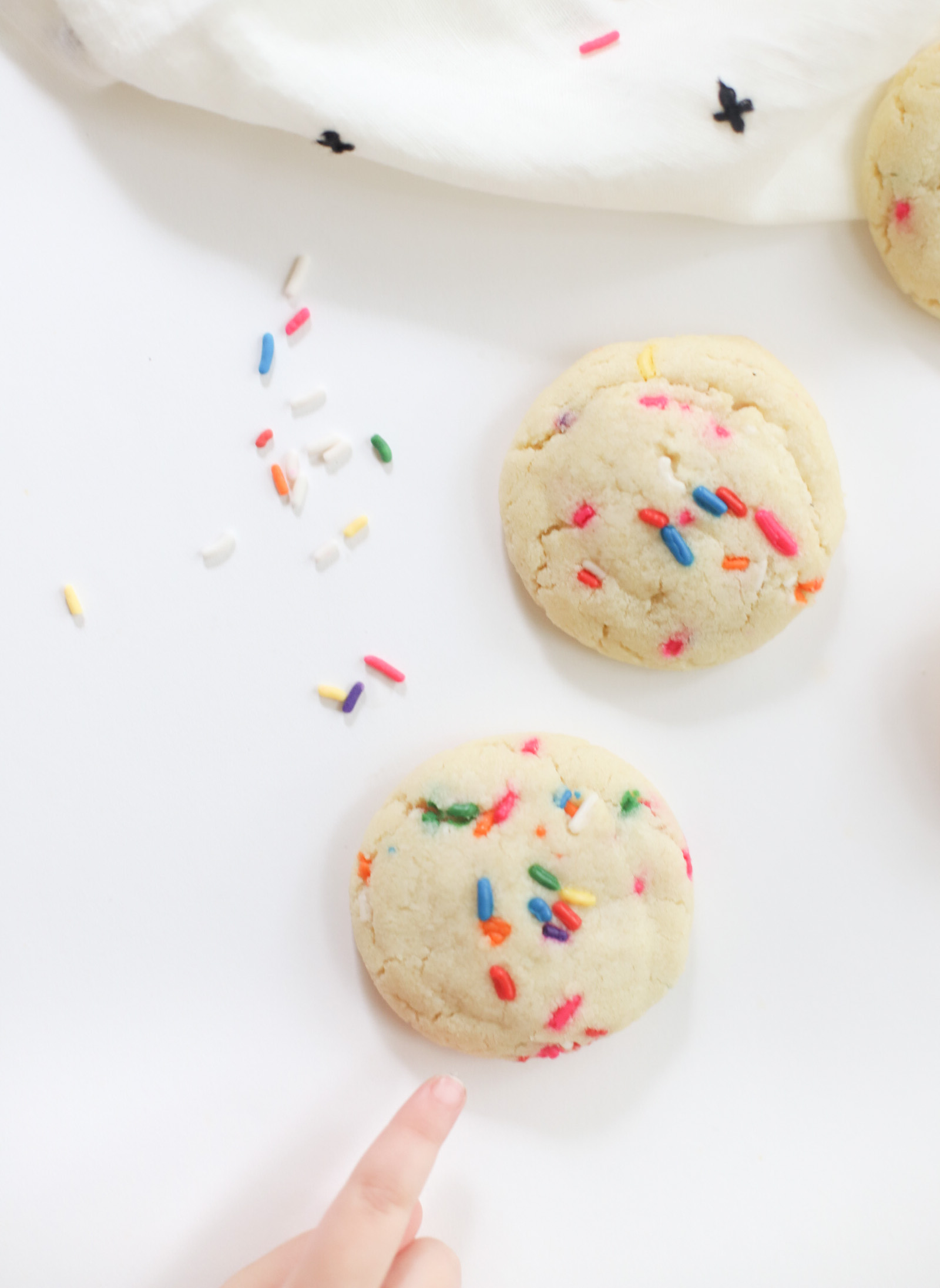 a child's finger pointing to a cooking with sprinkles 